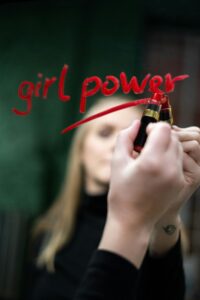 kobieta pisząca szminką na lustrze "girl power"