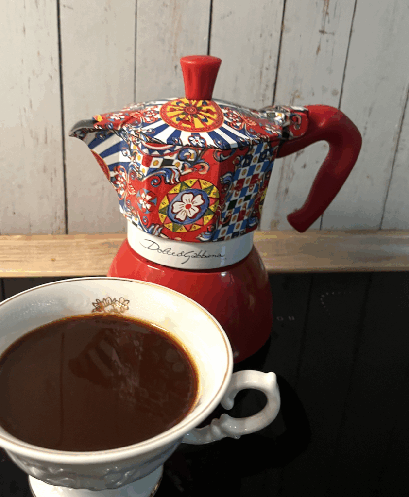 Kolorowa kawiarka za białą filiżanką z kawą