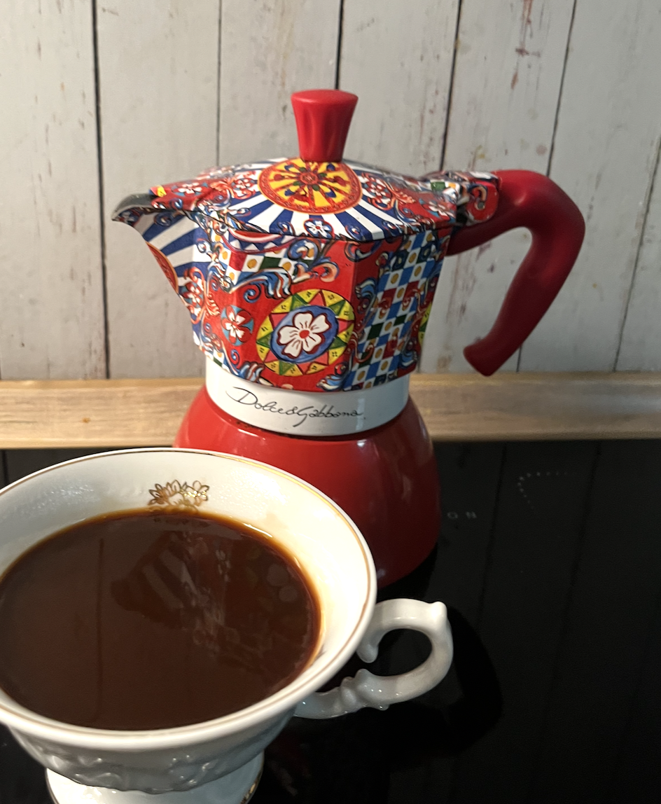 Kolorowa kawiarka za białą filiżanką z kawą