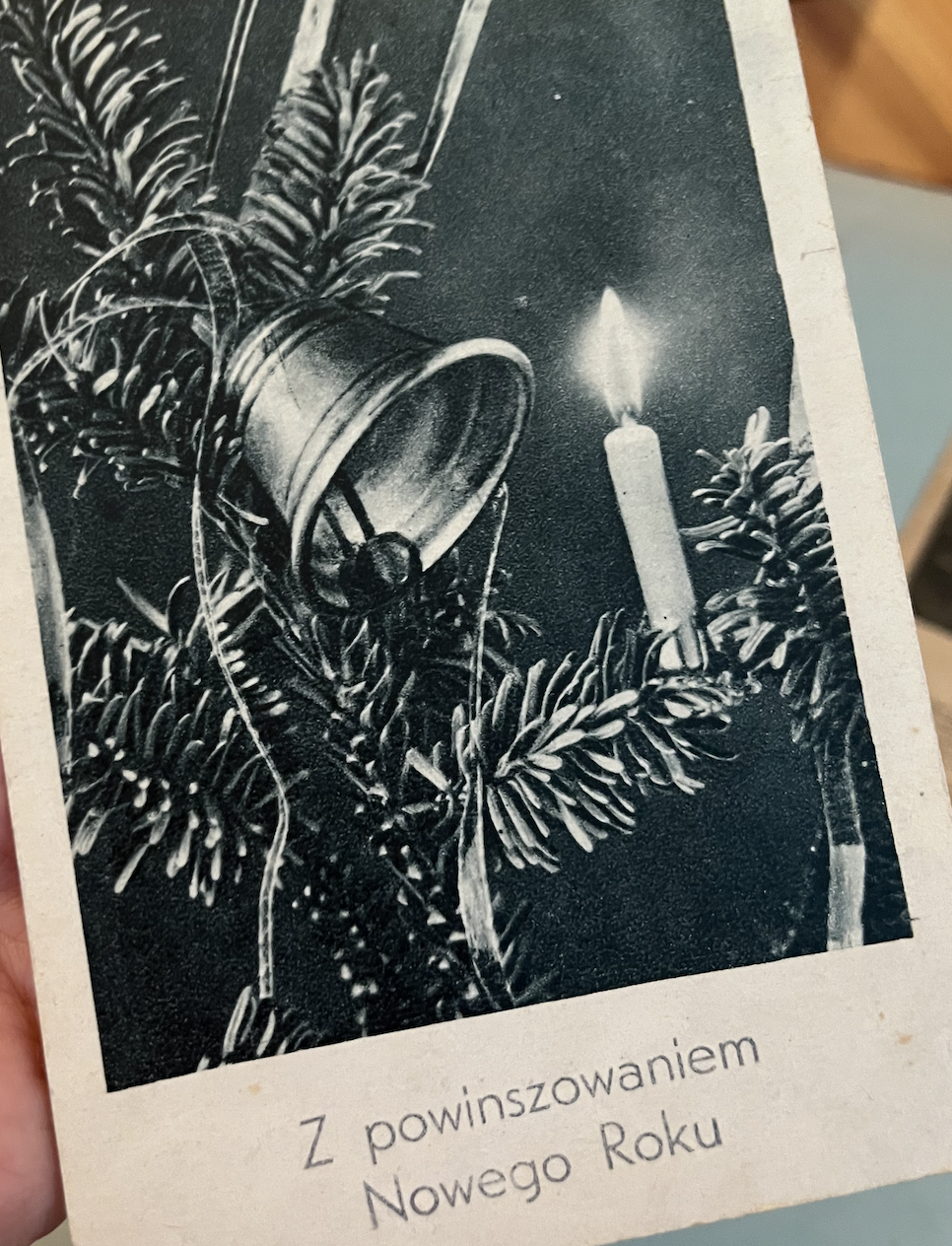 stara noworoczna pocztówka z choinką, dzwonkiem, świeczką i napisem "Z powinszowaniem Nowego Roku"