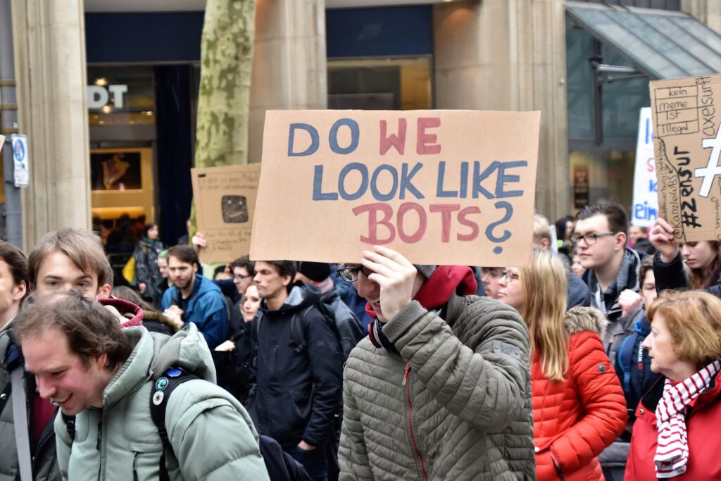 zdjęcie z protestu, ktoś trzyma tabliczkę z napisem "Do wee look like bots?"