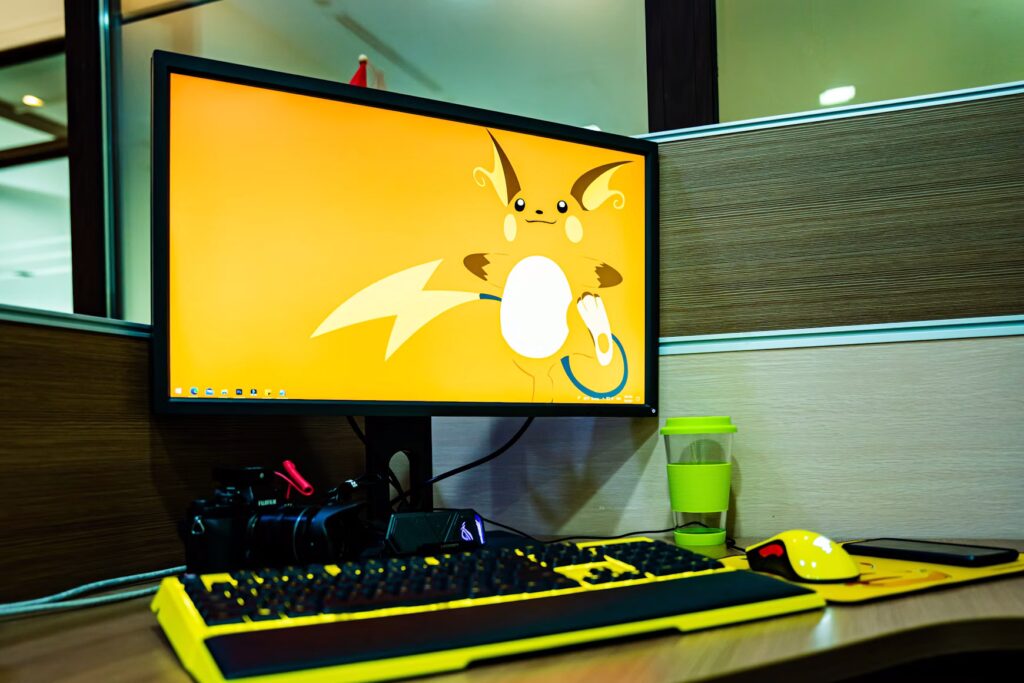 biurko z monitorem, na którym na tapecie jest pokemon