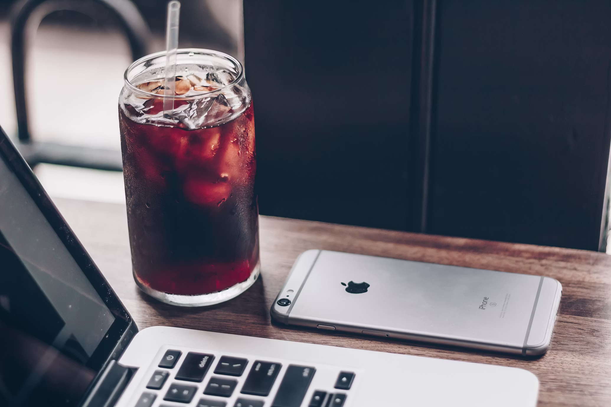 mrożona kawa z kostkami lodu lub cola, w tle laptop i smartfon
