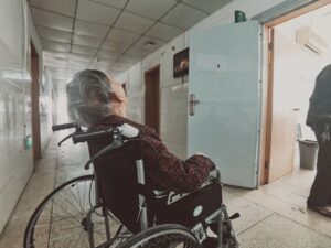 starsza osoba na wózku na szpitalnym korytarzu